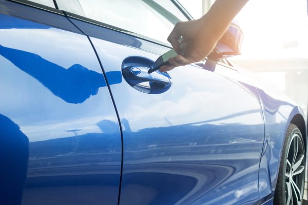 Selective focus of car door handle with blurred Male locking car using mobile application on smart phone. Concept innovation and modern of car ,New technologies digital key vehicle access